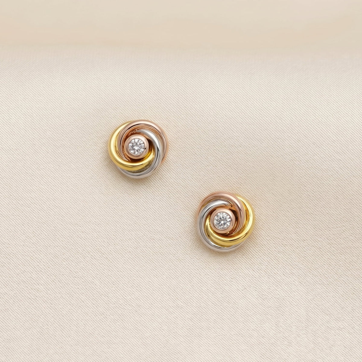 Round stud earrings in mixed vermeil featuring intertwined loops with a central sparkling lab-grown diamond, showcasing sculptural elegance in fine silver jewellery.