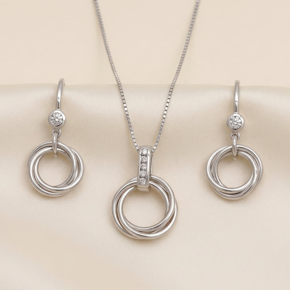 Sterling silver drop earrings featuring intertwined love knot circles accented with sparkling lab-grown diamonds, paired with a matching pendant for a cohesive elegant look.