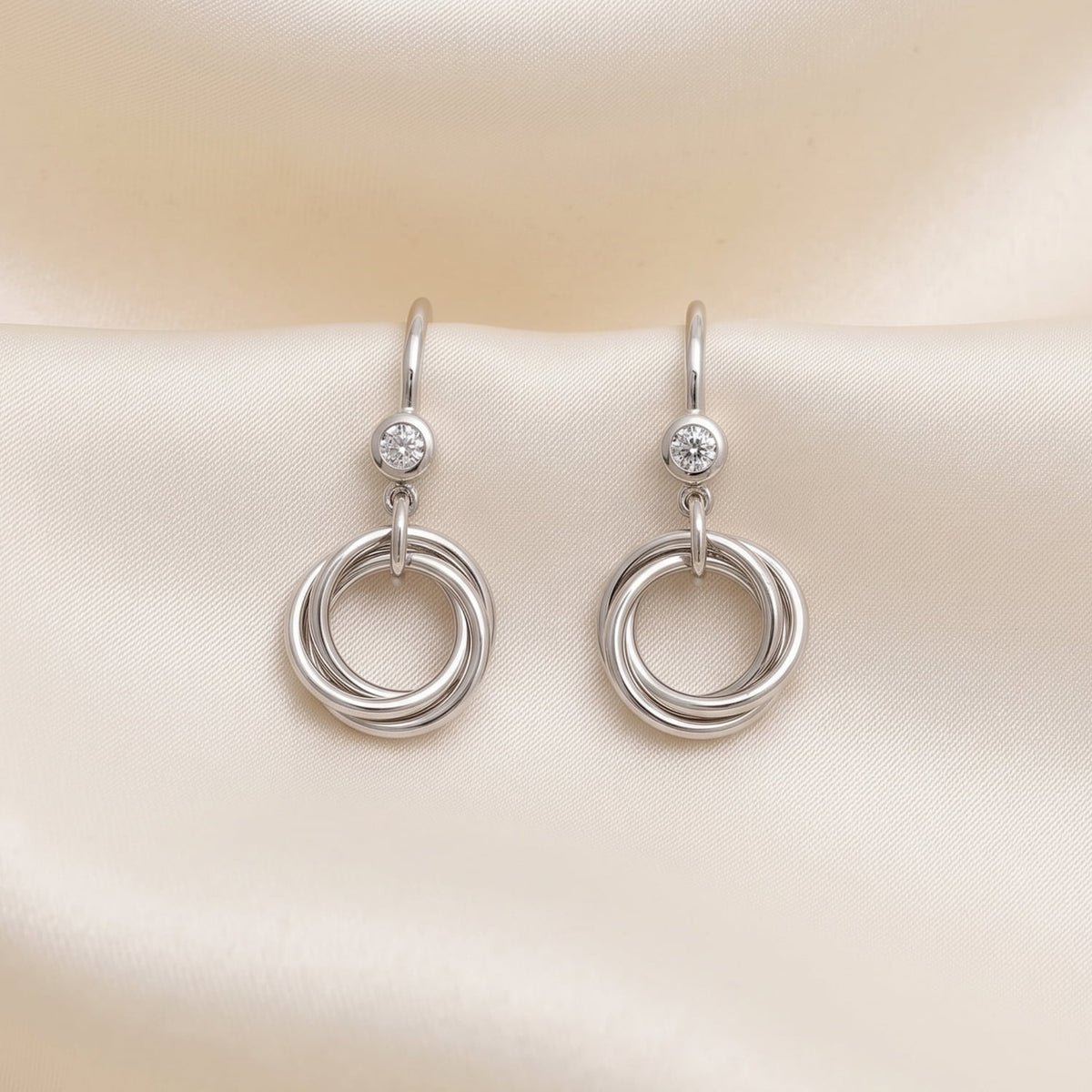 Sterling silver drop earrings featuring intertwined love knot hoops suspended from hooks set with sparkling lab grown diamonds, crafted with a contemporary British design.