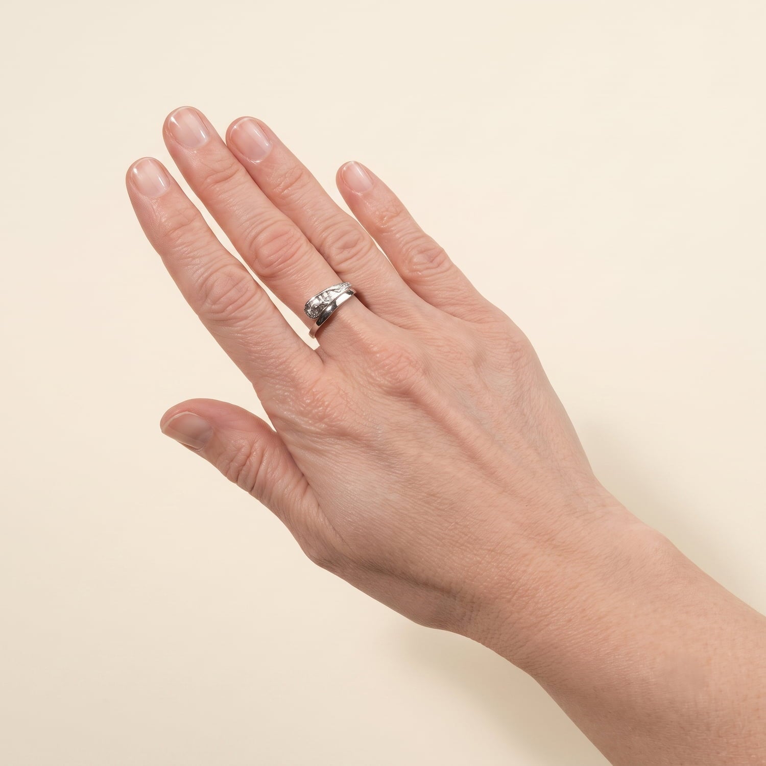 Model wears a sterling silver ring featuring a polished band with a contrasting textured sculptural detail, showcasing a modern and refined design for contemporary silver jewellery.
