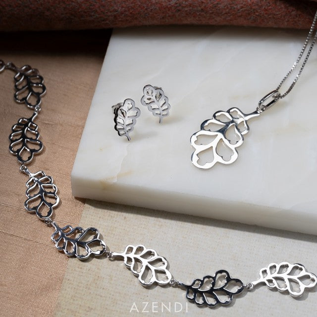 Sterling silver jewellery set featuring sculptural Yorkshire oak leaf motifs including a pendant necklace, matching earrings, and a linked bracelet displayed on a neutral surface.