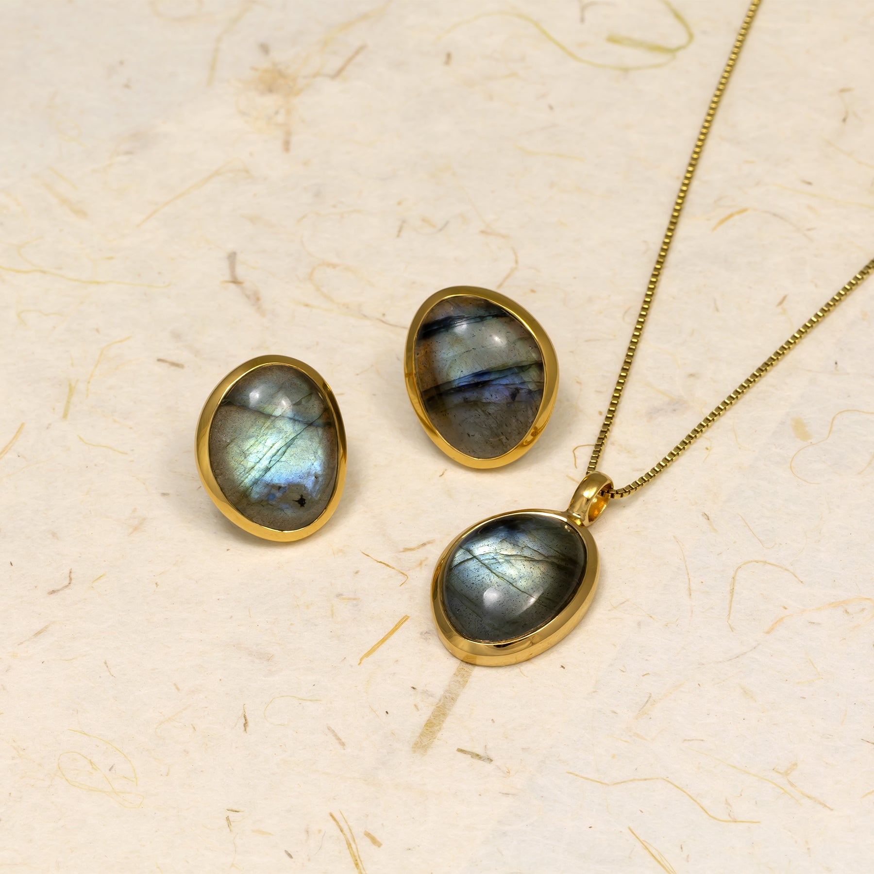 Gold vermeil oval-shaped stud earrings featuring iridescent spectrolite gemstones, paired with a matching pendant necklace, embodying elegant and sculptural design.