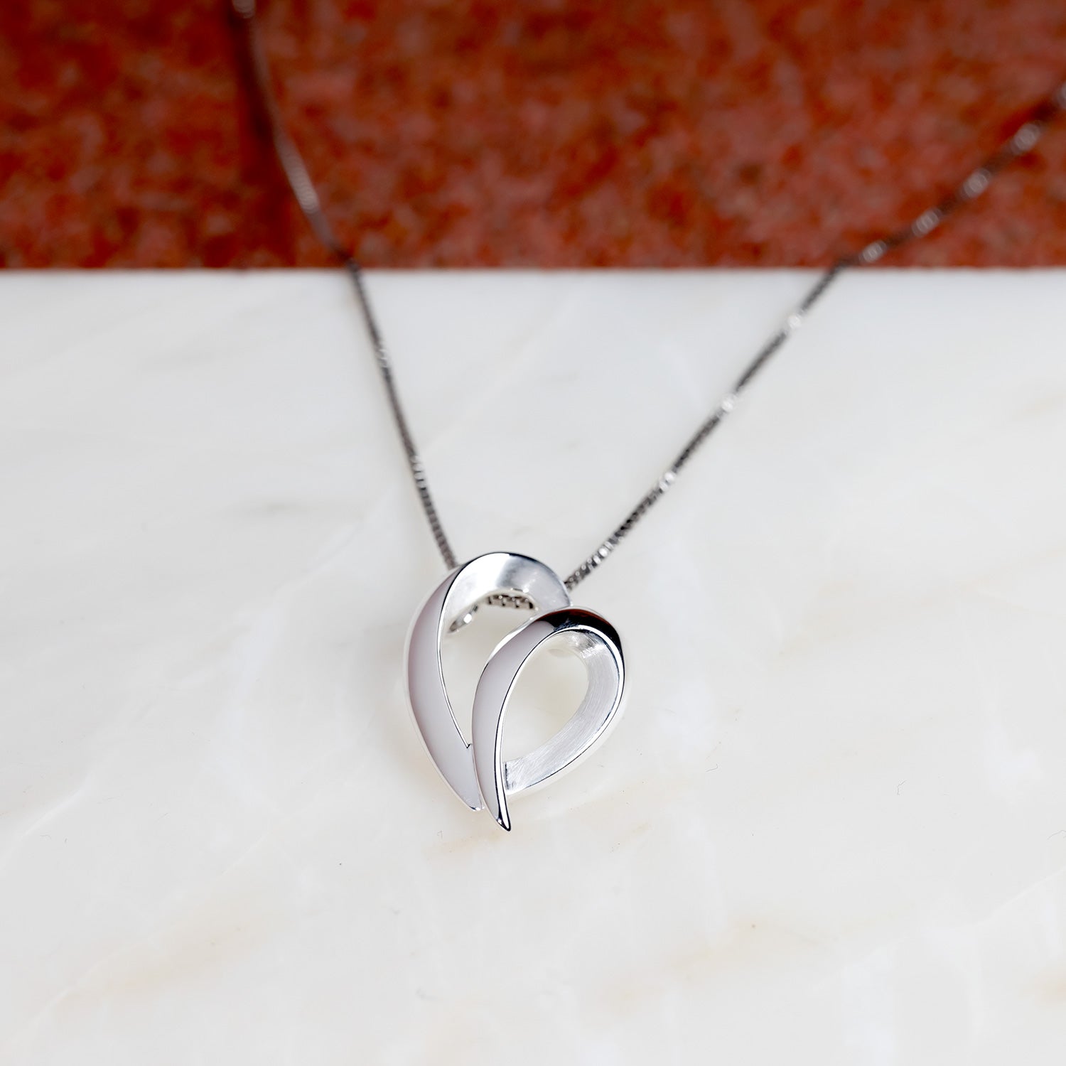Sleek sterling silver pendant shaped as an abstract heart with a flowing, sculptural form, suspended from a delicate fine chain for contemporary elegance.