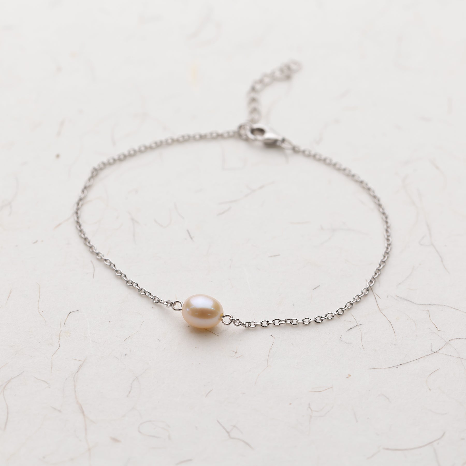 Delicate sterling silver bracelet featuring a single oval freshwater pearl on a fine chain with adjustable clasp for a refined and minimalist jewellery look.