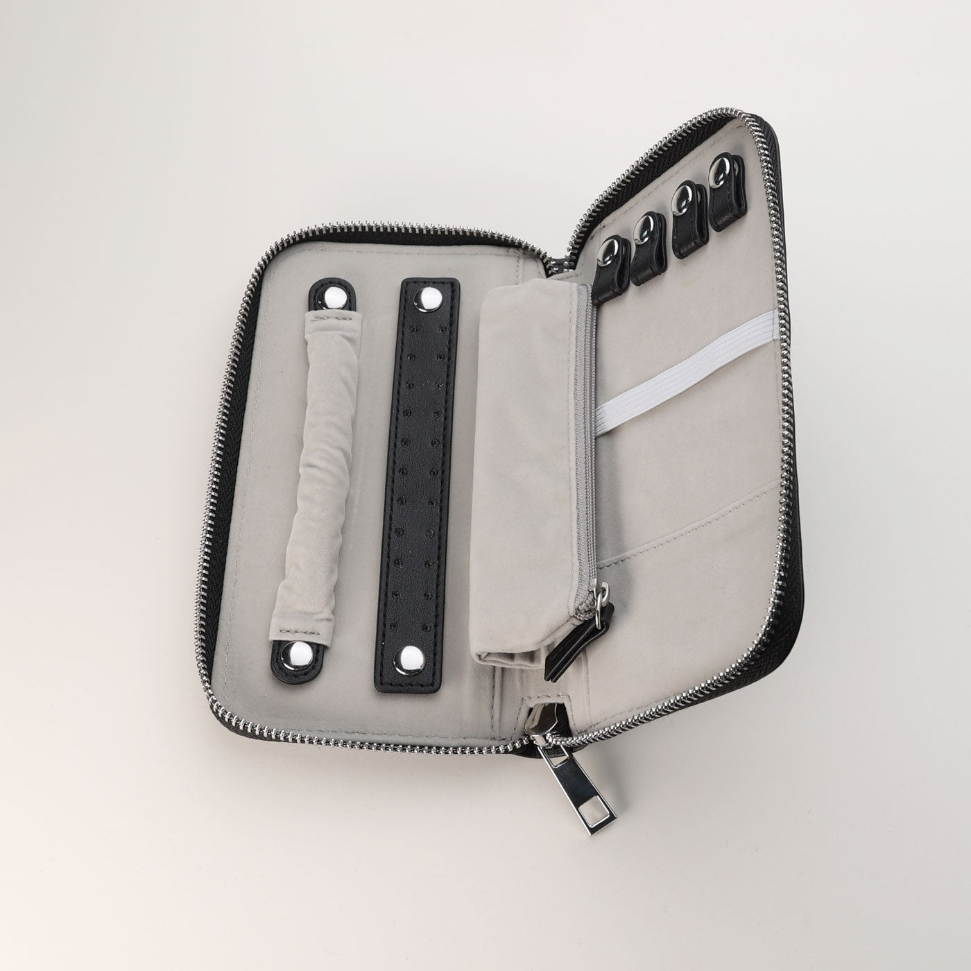 Open jewellery travel wallet in soft grey velvet and PU leather with multiple compartments and secure zipper closure, designed to protect and organise pieces while travelling.