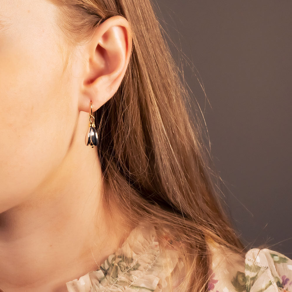 Delicate sterling silver earrings inspired by snowdrop flowers, featuring subtle sculptural drops that hang gracefully from gold vermeil hooks for a refined look.