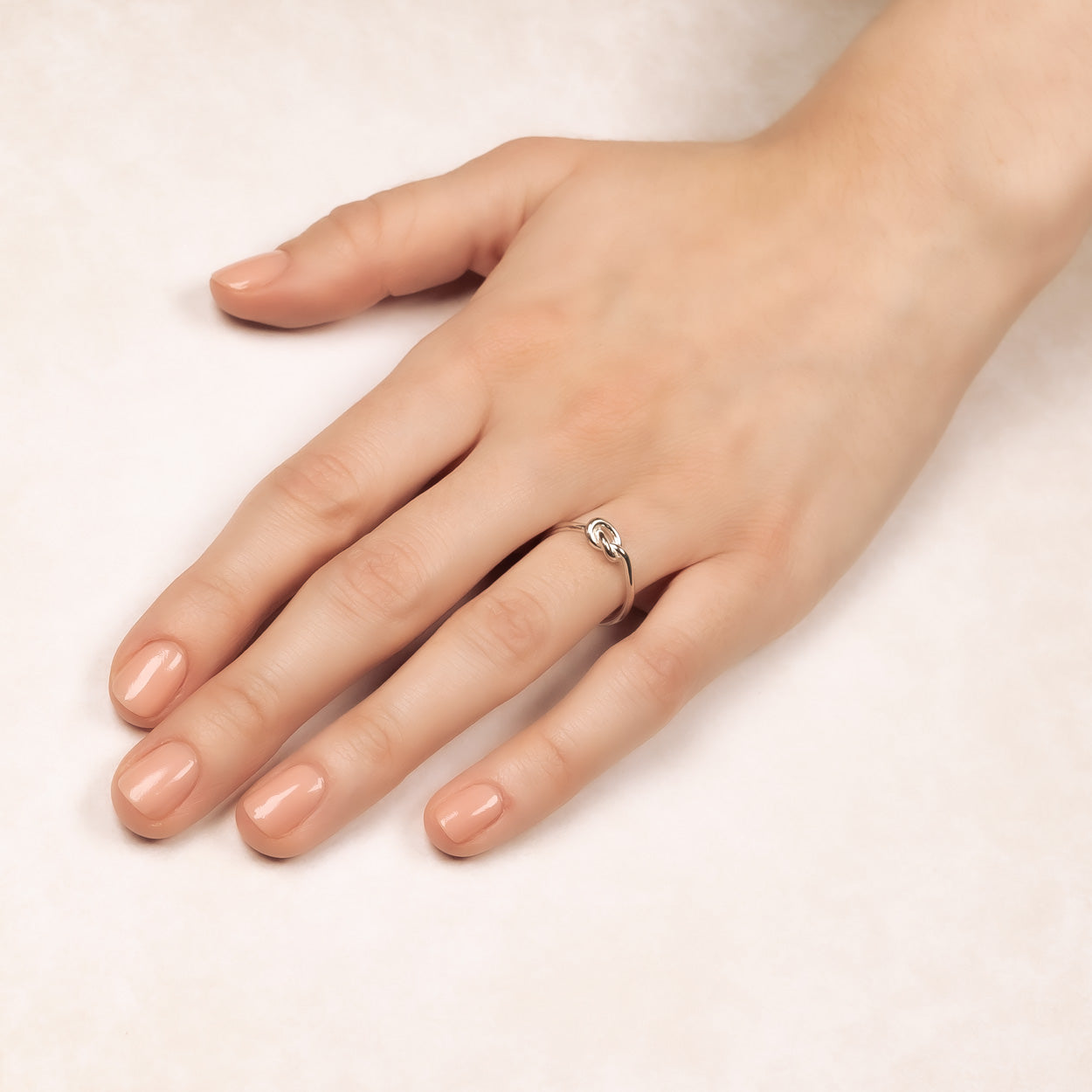Sterling silver ring featuring a sculptural knot design delicately resting on a hand, showcasing refined minimalist elegance in British designer jewellery.