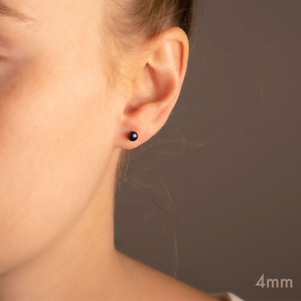 Close-up of an ear wearing a polished sterling silver stud earring featuring a deep peacock pearl, showcasing understated elegance in fine silver jewellery design.