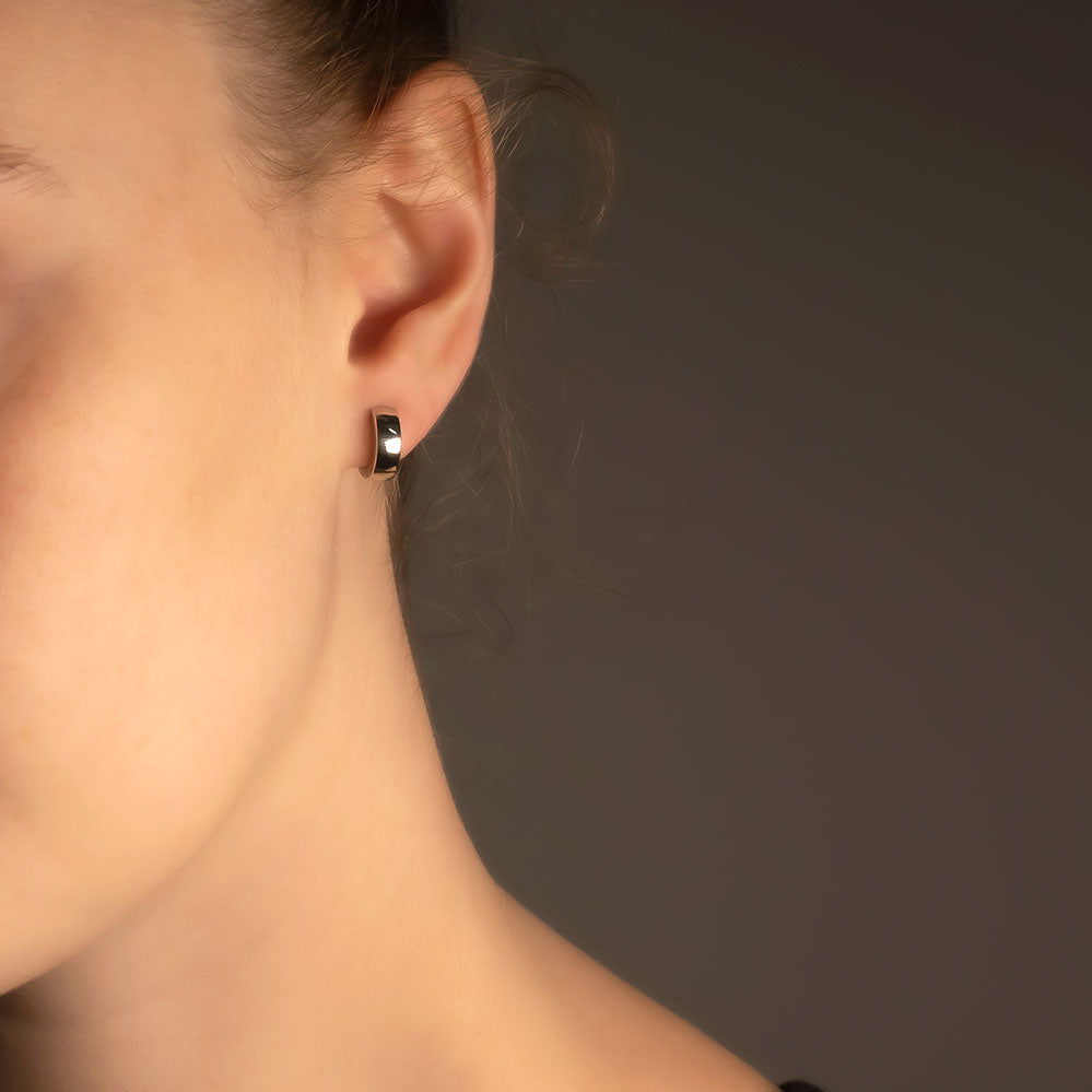 Small wide sterling silver hoop earring with a polished finish, showcasing a modern, sculptural design by an award-winning British jeweller.