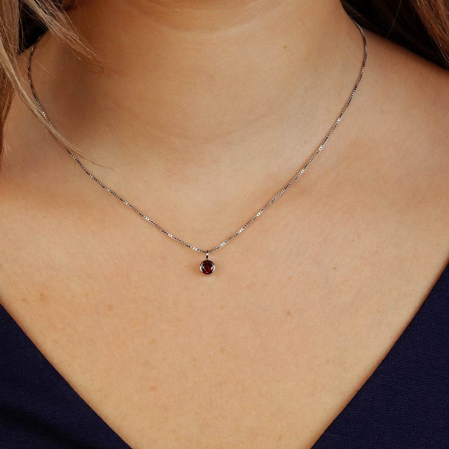 Delicate sterling silver pendant featuring a deep red garnet gemstone, suspended on a fine chain, exemplifying expert British craftsmanship with a refined and minimalist design.