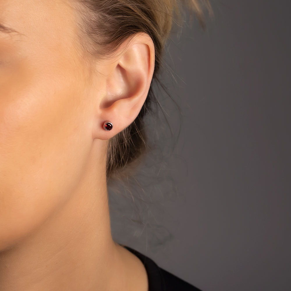 Delicate sterling silver stud earrings featuring deep red garnet January birthstones, showcasing a refined and timeless design by an award-winning British jeweller.