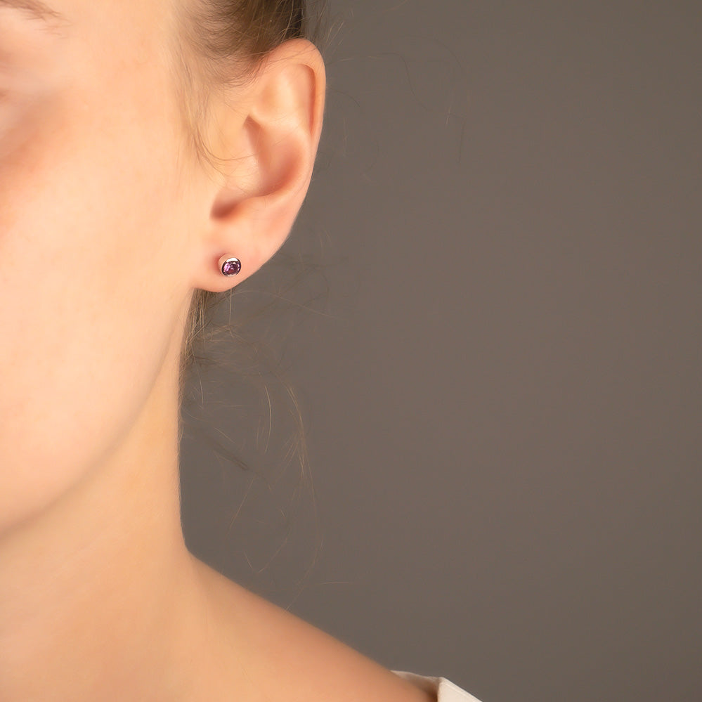 Delicate sterling silver stud earrings featuring deep purple amethyst gemstones, exemplifying expert British craftsmanship with a refined and minimalist design.