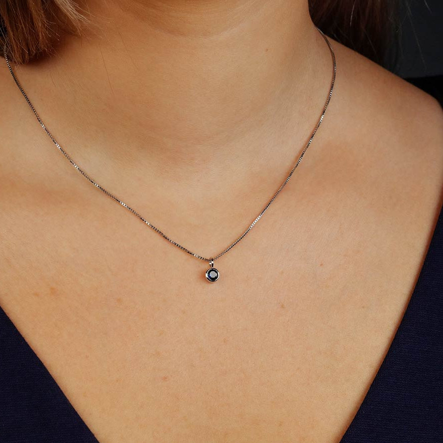 Delicate sterling silver necklace featuring a sculptural pendant with a deep blue spinel gemstone, exemplifying refined British craftsmanship and contemporary design.