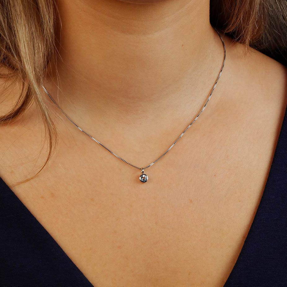 Delicate sterling silver necklace featuring a single blue topaz pendant, embodying refined craftsmanship and a subtle, elegant design.