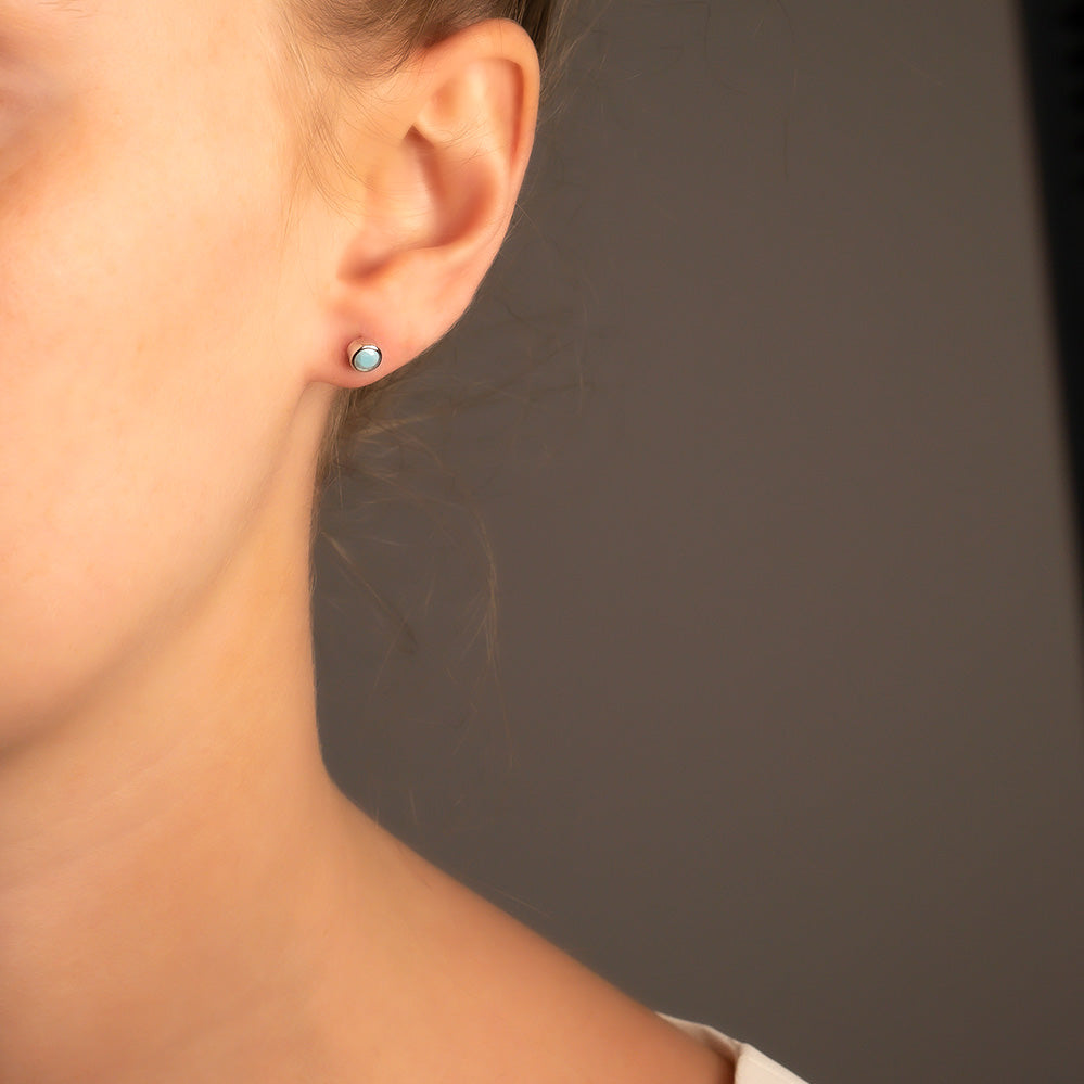 Delicate sterling silver stud earrings featuring vibrant turquoise stones, showcasing a refined, contemporary design by an award-winning British jeweller.