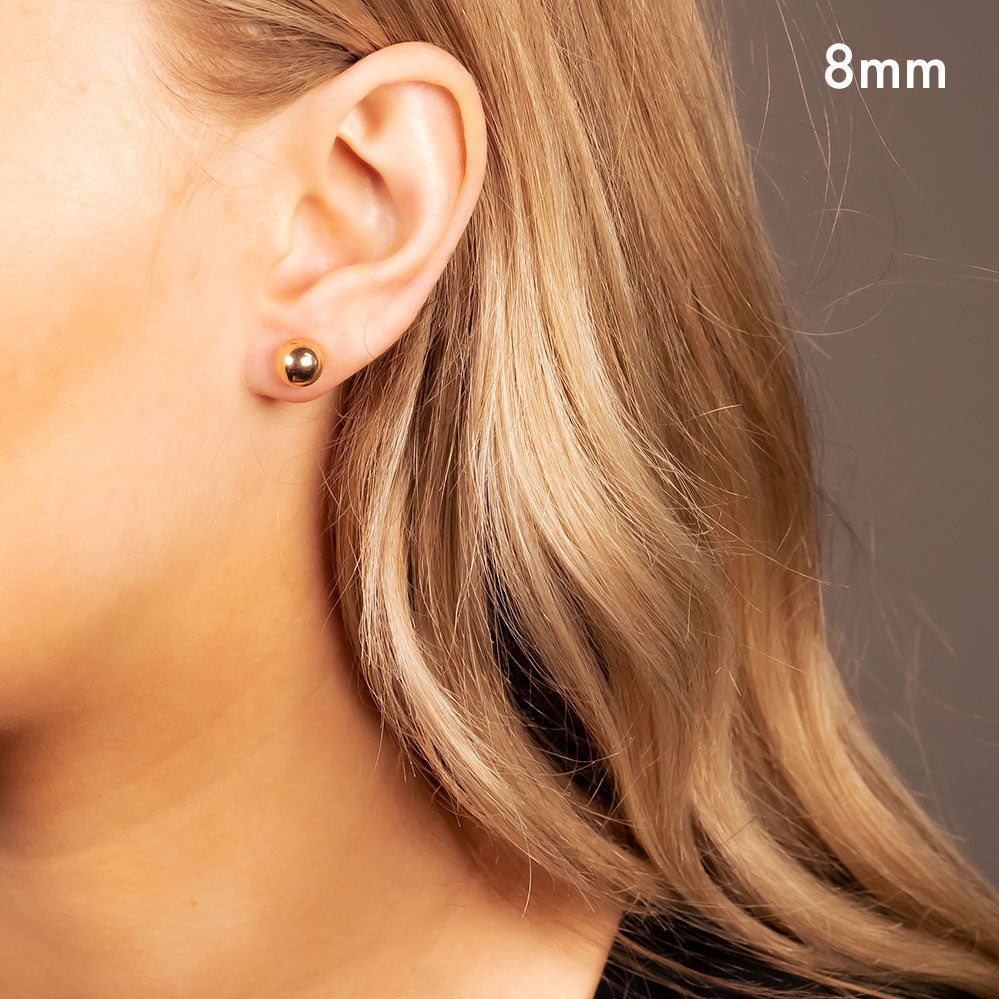 Single polished rose gold vermeil ball stud earring worn on the earlobe, showcasing a sleek and minimalist design from a contemporary British sterling silver jewellery collection.
