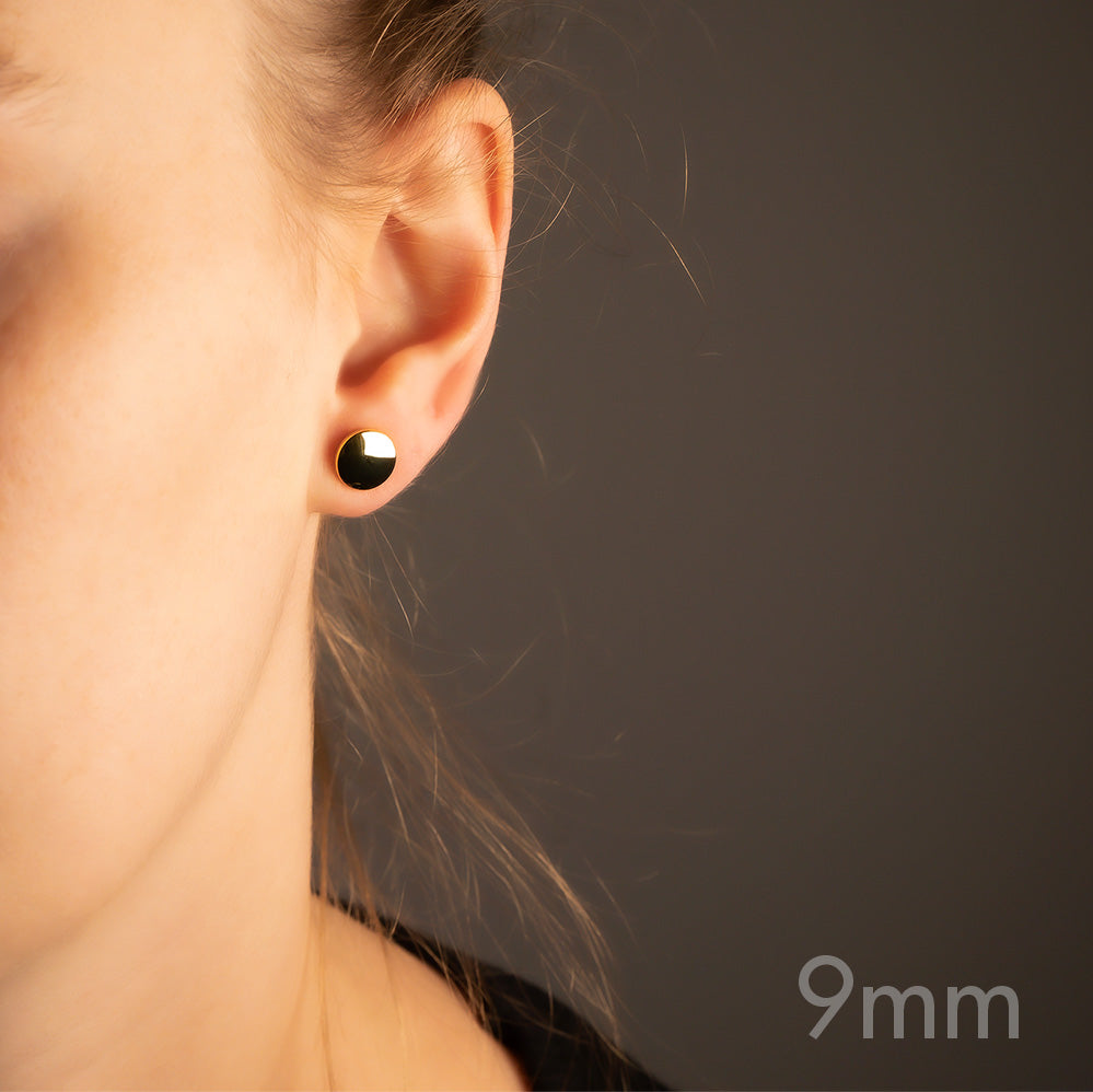 Minimalist yellow gold vermeil button stud earring with a gently curved surface, worn on the earlobe for a refined and contemporary sterling silver jewellery look.