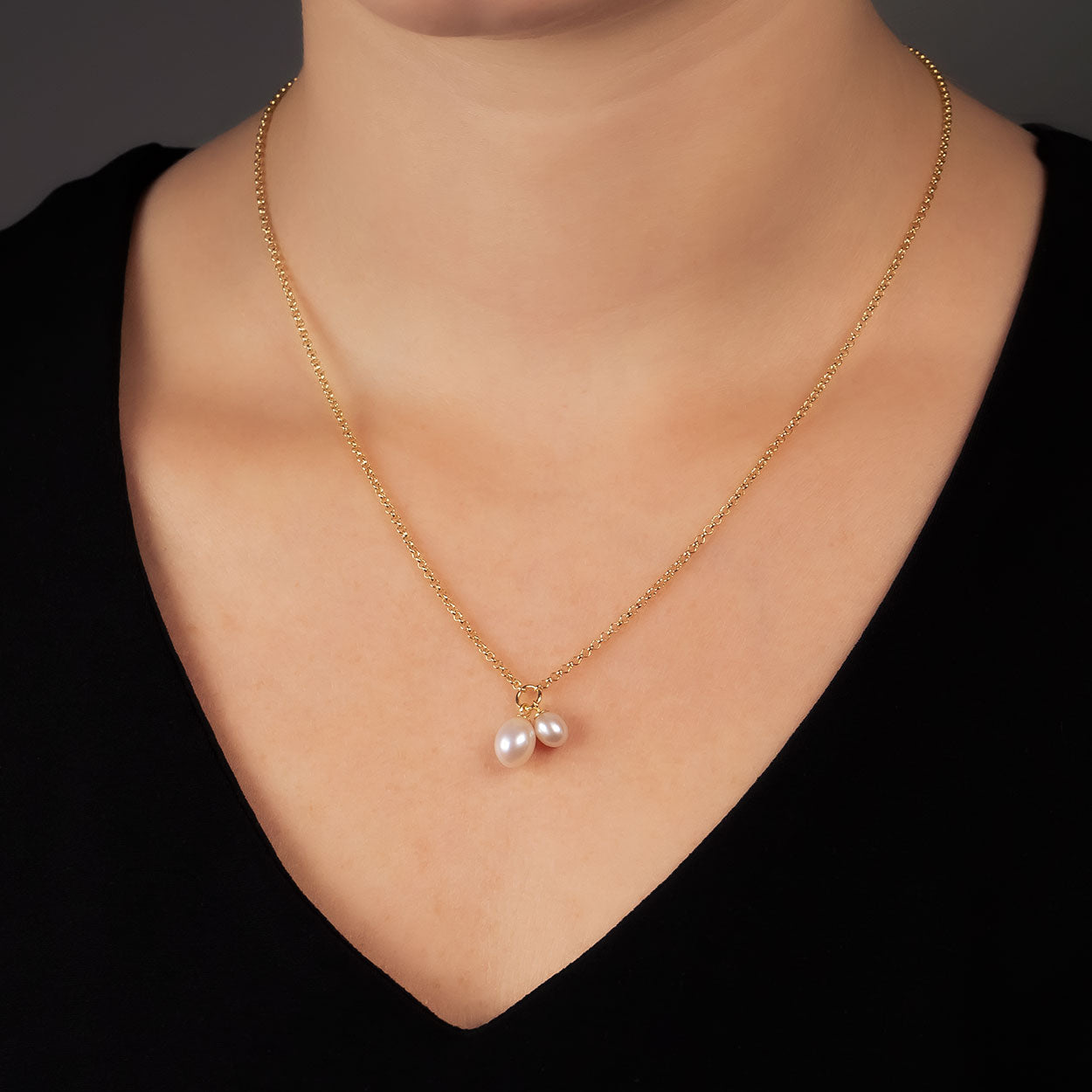 Delicate gold vermeil necklace featuring two teardrop-shaped freshwater pearls on an adjustable chain, styled against a black top for a timeless elegant look.