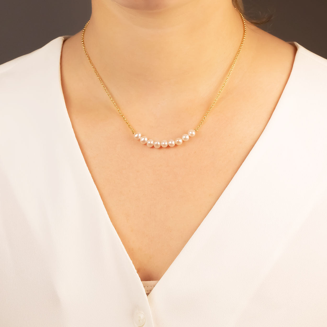 Gold vermeil necklace featuring a delicate strand of nine lustrous pearls, elegantly resting against a white blouse for a minimalist and refined sterling silver jewellery look.
