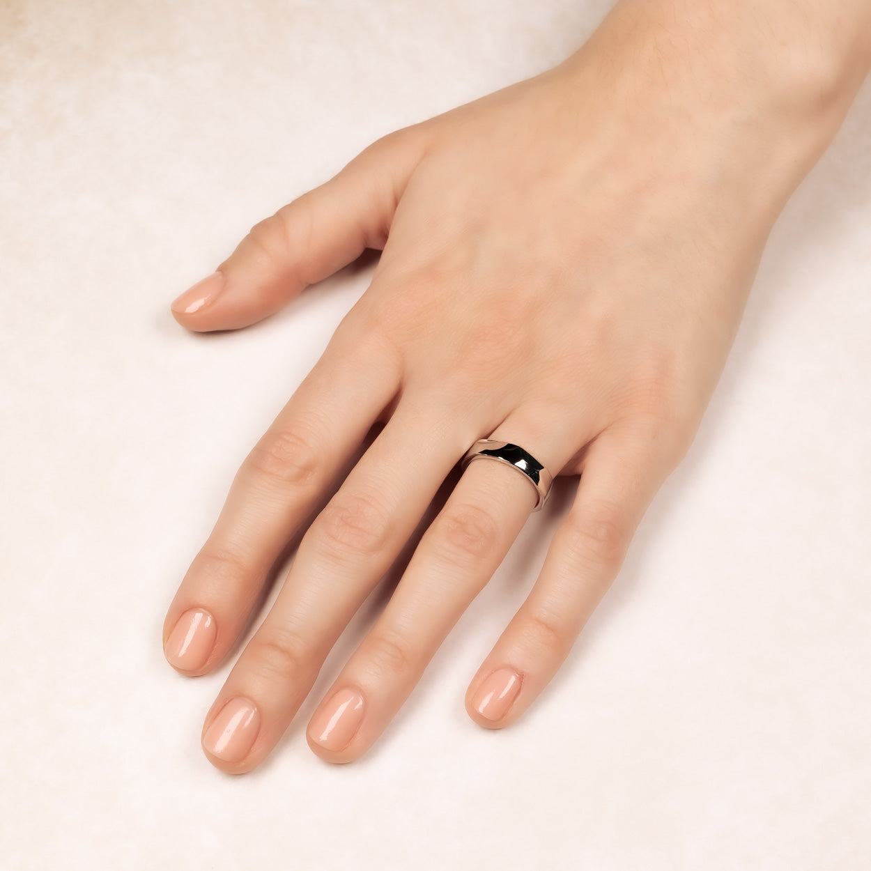 Hand showcasing a polished sterling silver ring with a faceted surface, highlighting its sculptural design and contemporary elegance in fine silver jewellery by Azendi.