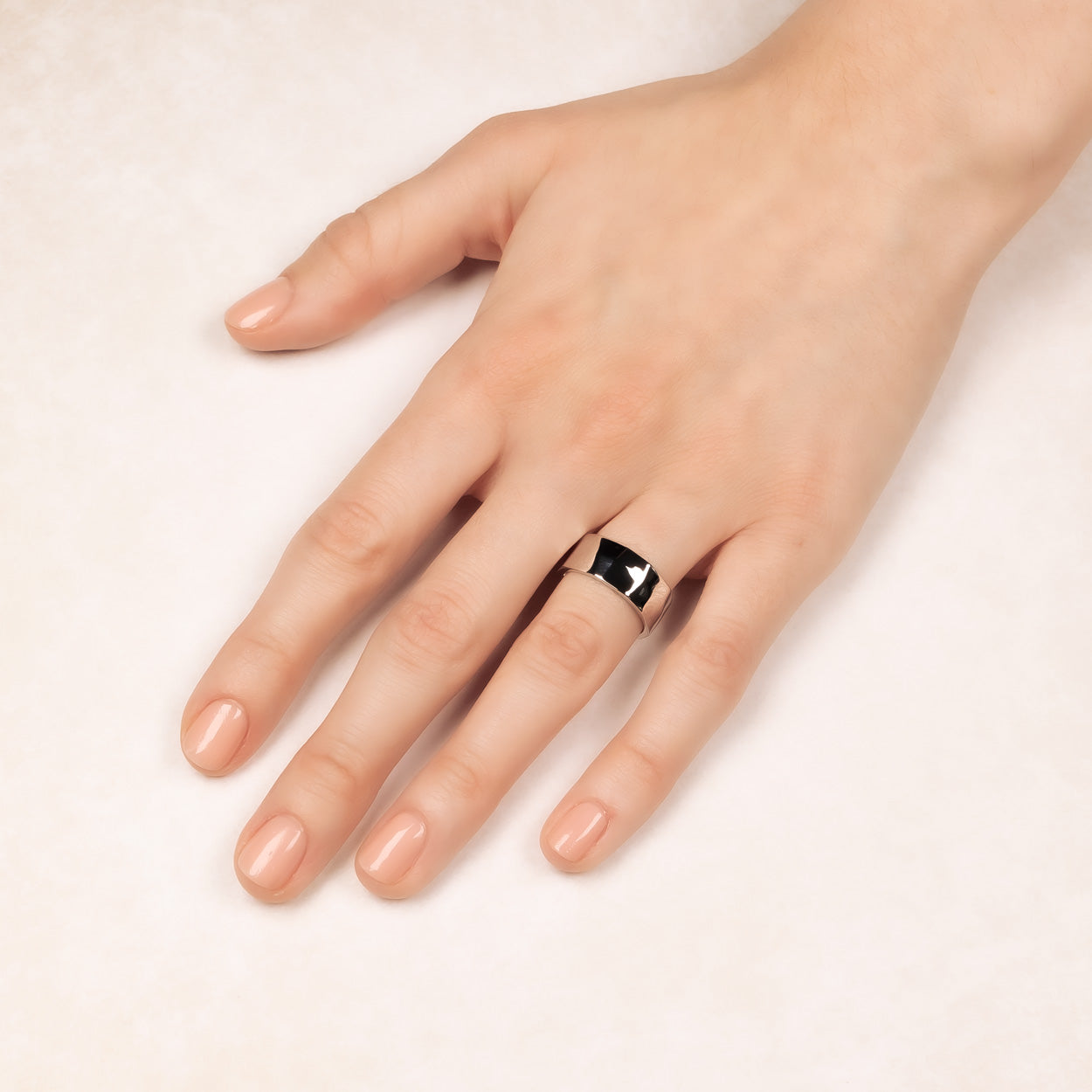 Hand wearing a polished sterling silver ring with a distinctive faceted surface, showcasing a contemporary and sculptural design in fine silver jewellery.
