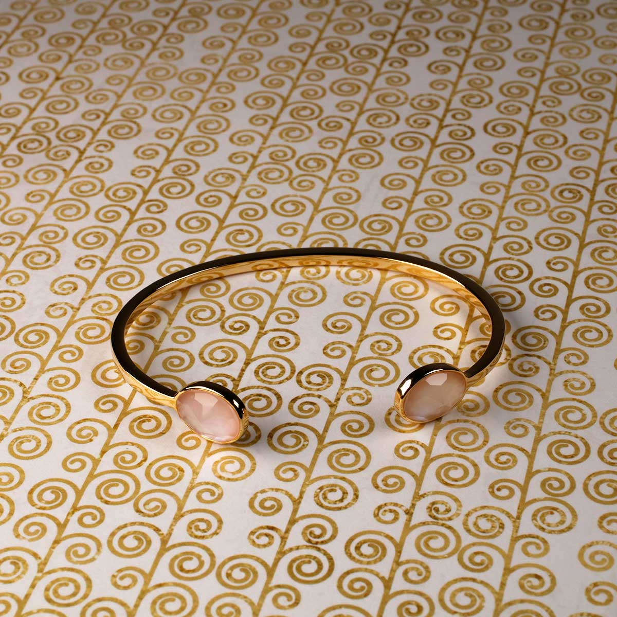 Open gold vermeil cuff bracelet featuring two teardrop-shaped mother of pearl stones, set against a decorative patterned background for a refined look.