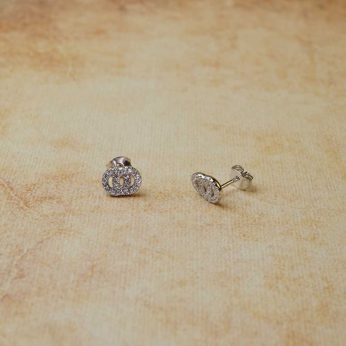 Pair of sterling silver stud earrings featuring interlocking circles paved with sparkling cubic zirconia stones, showcasing refined and sculptural silver jewellery design.