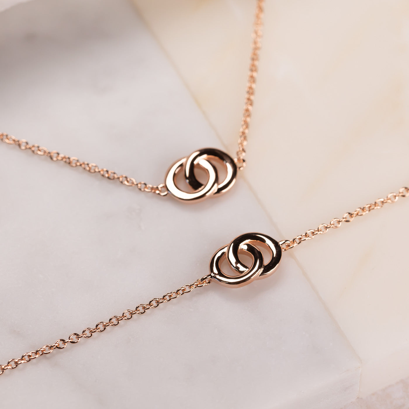 Two delicate rose gold vermeil bracelets featuring interlocking circular motifs on fine adjustable chains, embodying a modern and sculptural design aesthetic.