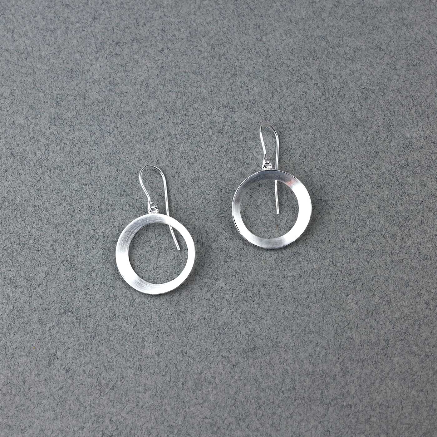 Pair of silver drop earrings featuring smooth, satin-finished circular hoops with a contemporary design, exemplifying refined sterling silver jewellery by Azendi.