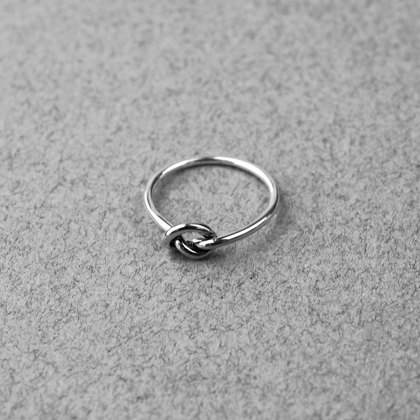 Sterling silver ring featuring a sculptural knot design with a slender band, showcasing refined contemporary jewellery with a minimalist aesthetic.