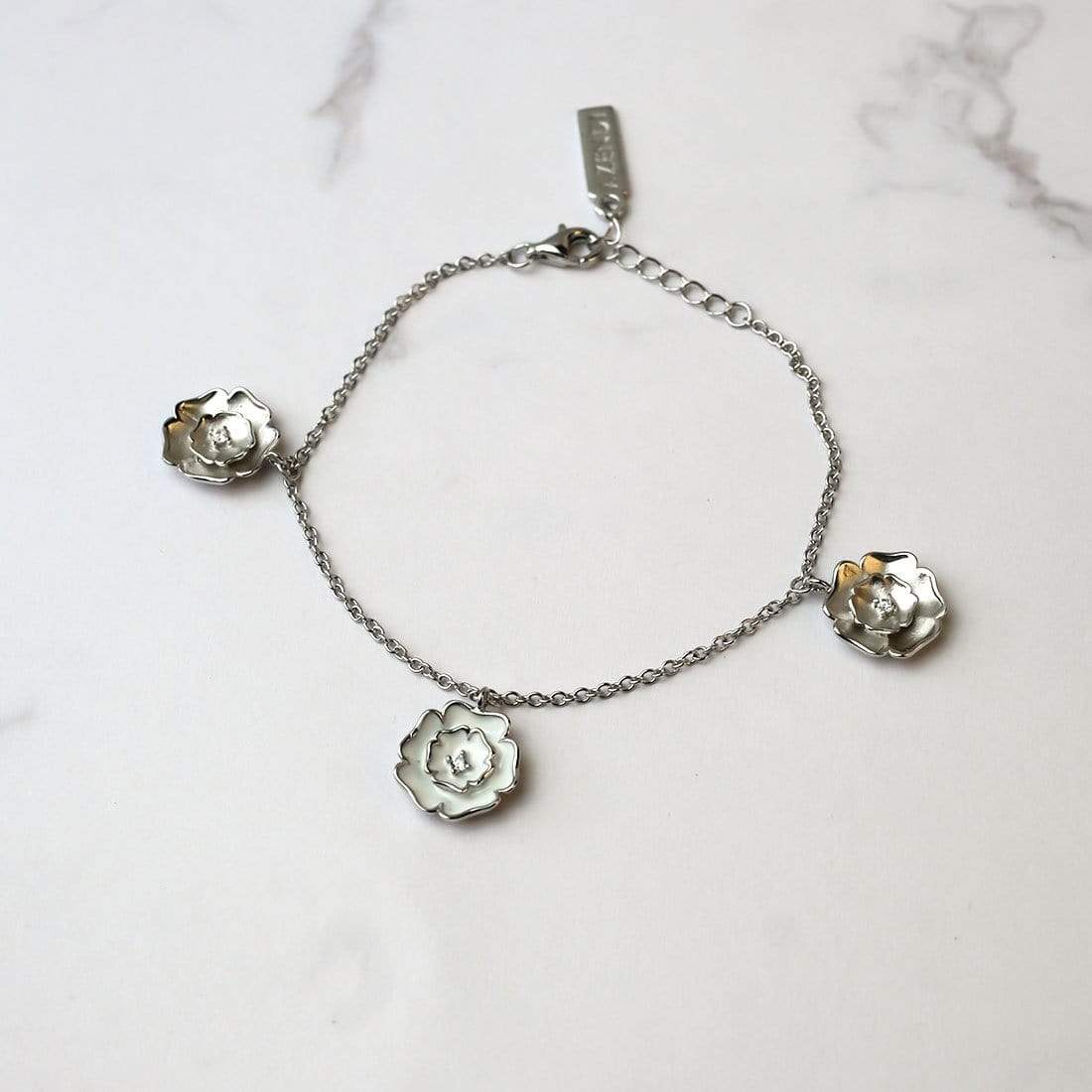 Delicate sterling silver bracelet featuring three Yorkshire rose charms with white enamel accents, showcasing a refined and sculptural design in contemporary silver jewellery by Azendi.