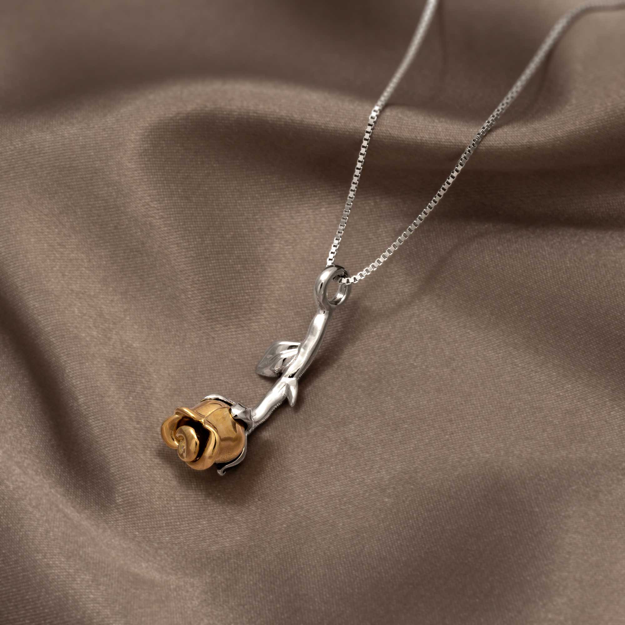 Sterling silver pendant featuring a sculptural rose with gold vermeil petals on a delicate chain, showcasing contemporary British craftsmanship and elegant design.