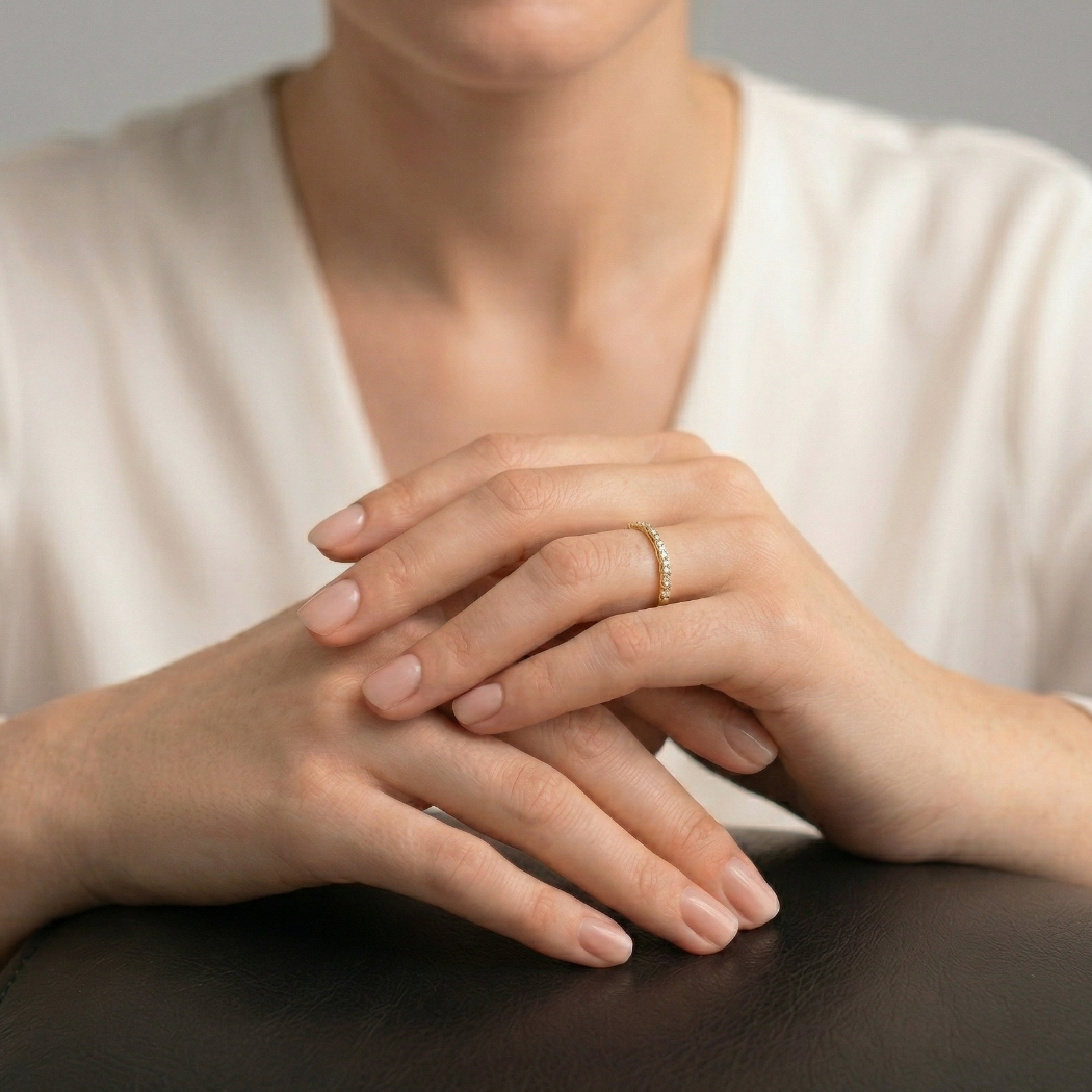 Delicate gold vermeil pavé eternity ring with a slender band, worn on a hand resting gently on a dark surface, highlighting its elegant and timeless design.