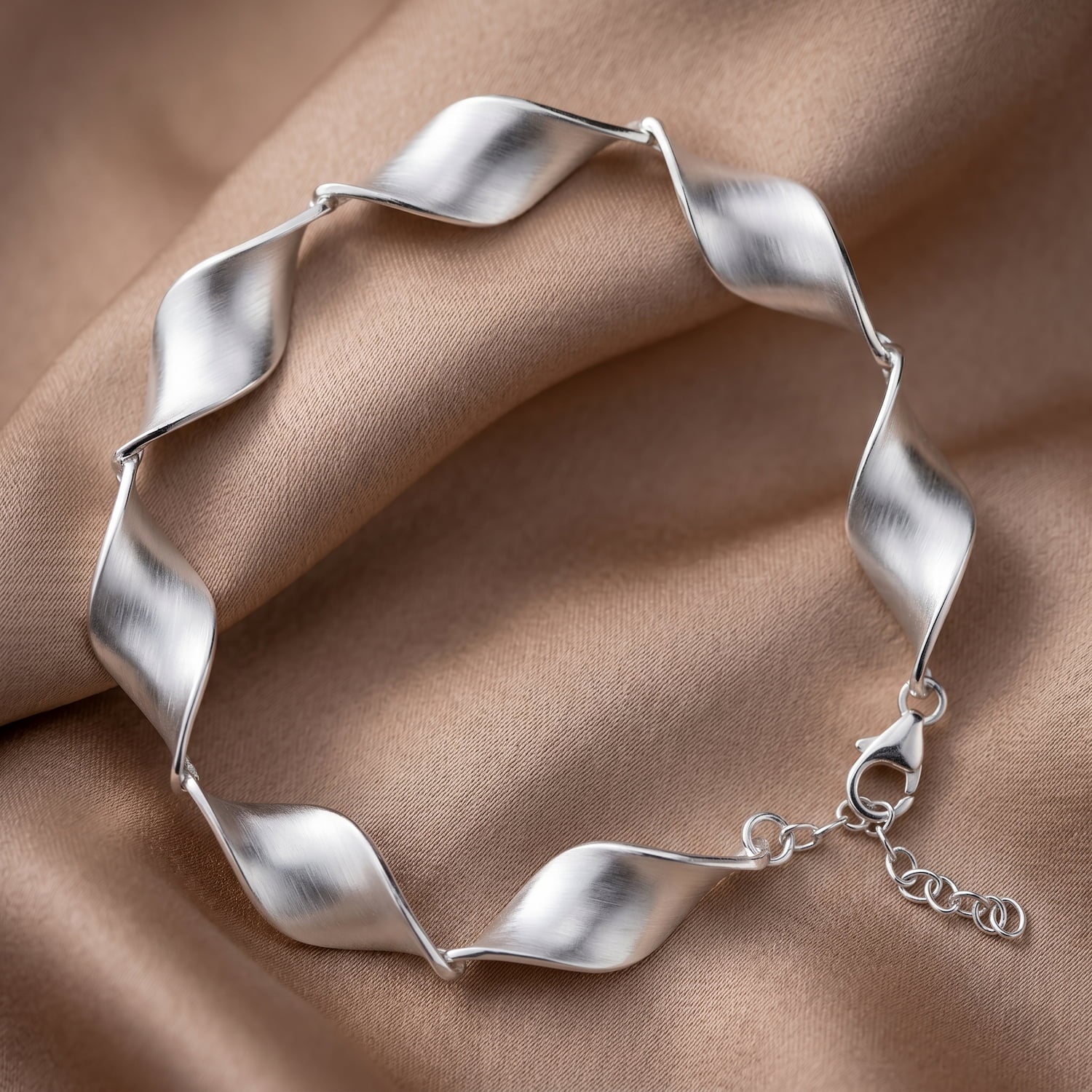 Silver bracelet with wavy design on a beige fabric background
