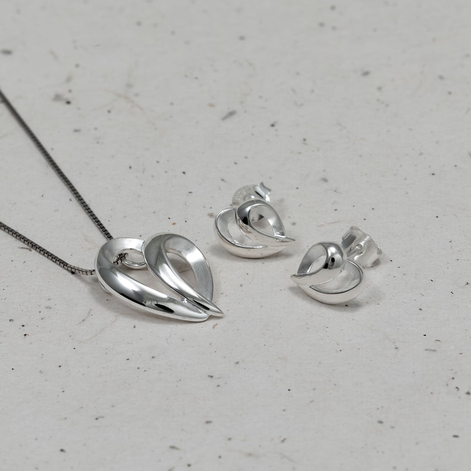 Sculptural sterling silver earrings featuring a dynamic, flowing heart-inspired form with a polished finish, embodying contemporary elegance in silver jewellery.