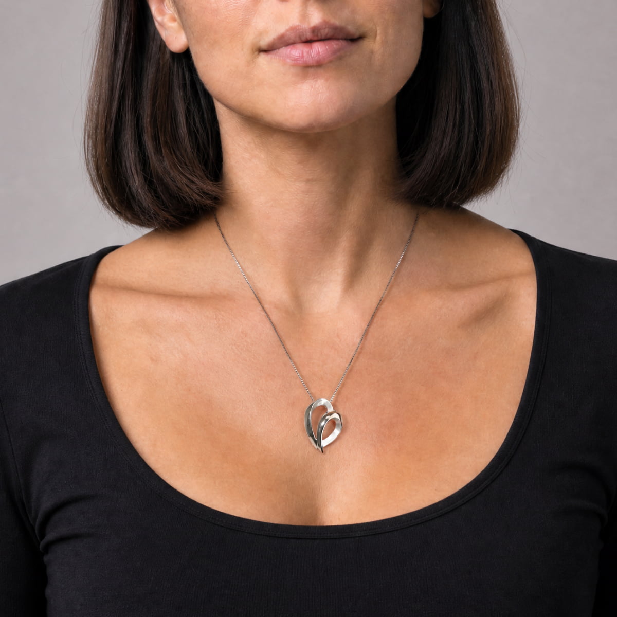 Sleek sterling silver pendant featuring an open heart design with smooth, flowing lines, suspended from a delicate fine chain for elegant, contemporary silver jewellery.