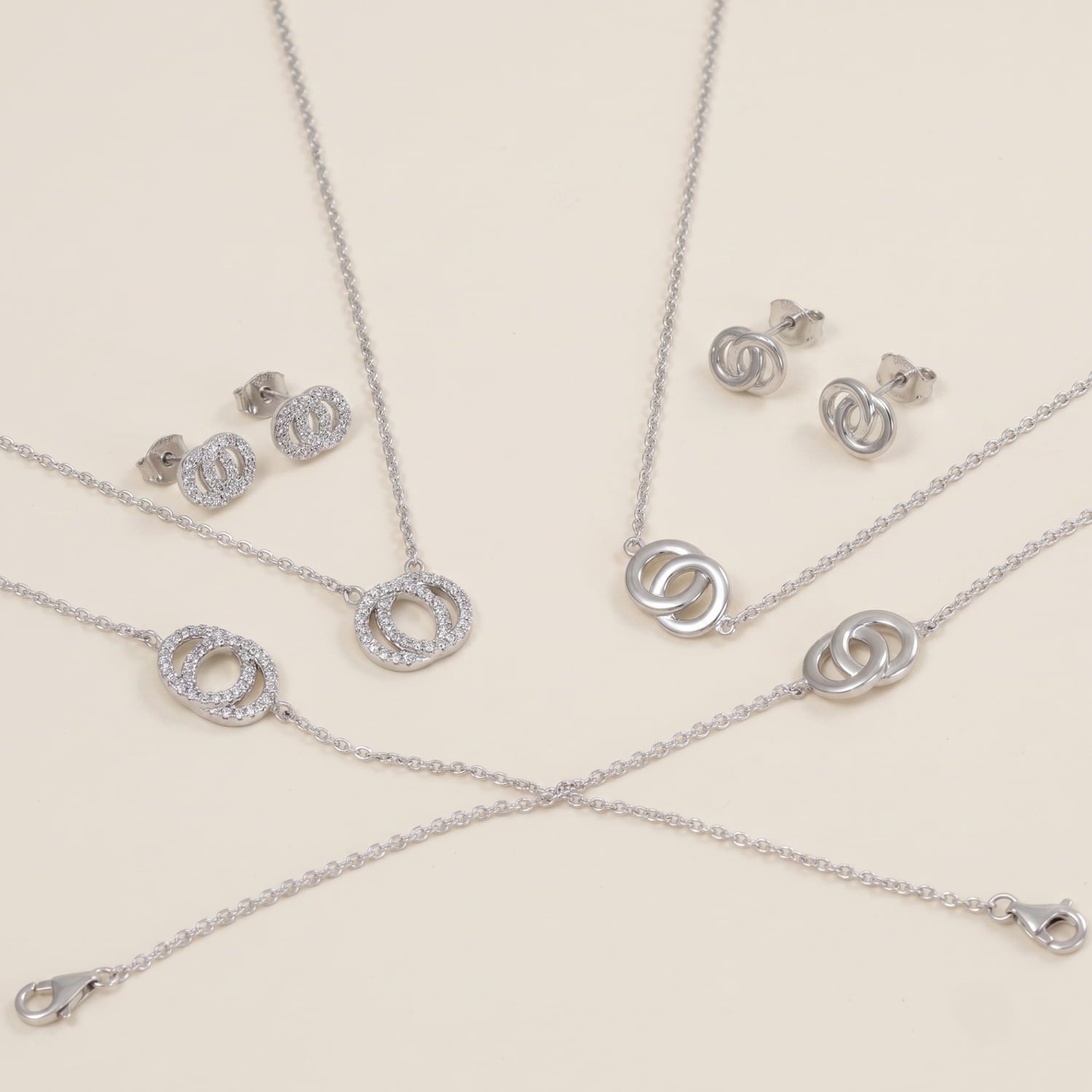 Collection of sterling silver jewellery including interlocking circle stud earrings and matching necklaces, featuring a contemporary sculptural design with polished and textured finishes.