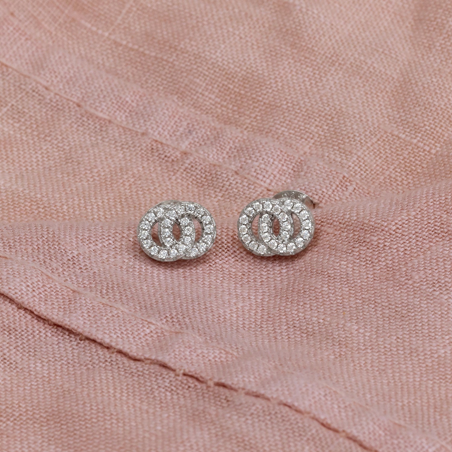 Pair of sterling silver stud earrings featuring interlocking circle design embellished with sparkling cubic zirconia, highlighting a modern and elegant style.