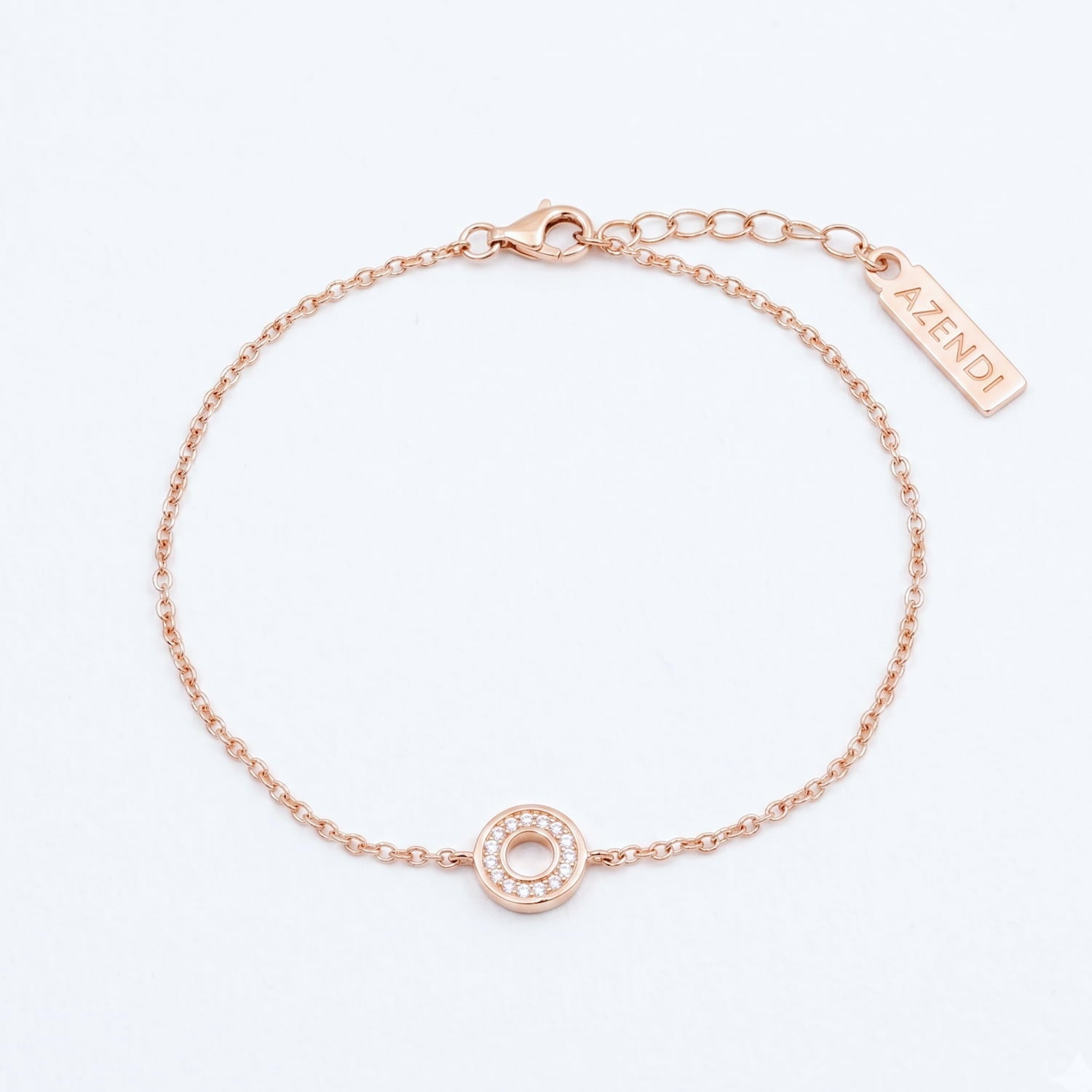 A rose gold vermeil bracelet with a small open circle charm adorned with cubic zirconia stones, displayed against a white background.