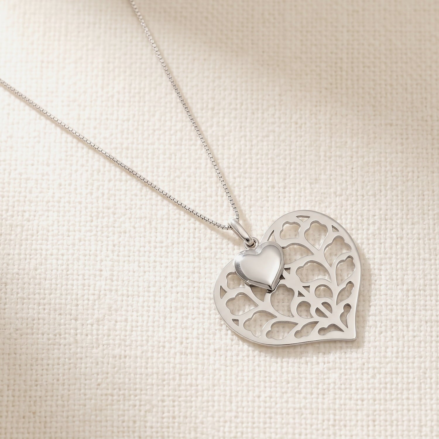 Sterling silver pendant featuring a sculptural double heart design with intricate openwork detailing, suspended on a delicate matching chain for elegant wear.