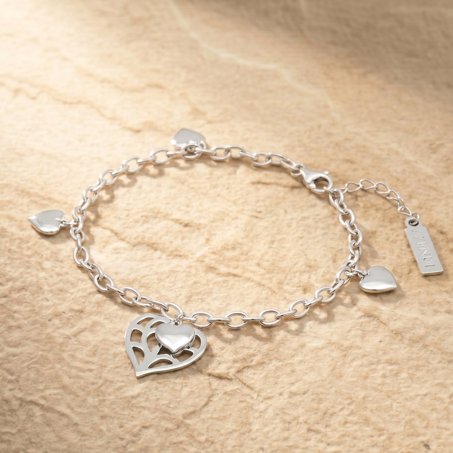 Sterling silver bracelet with an adjustable chain featuring four polished heart charms and a larger openwork heart charm inspired by Yorkshire design. Placed on a slate background.