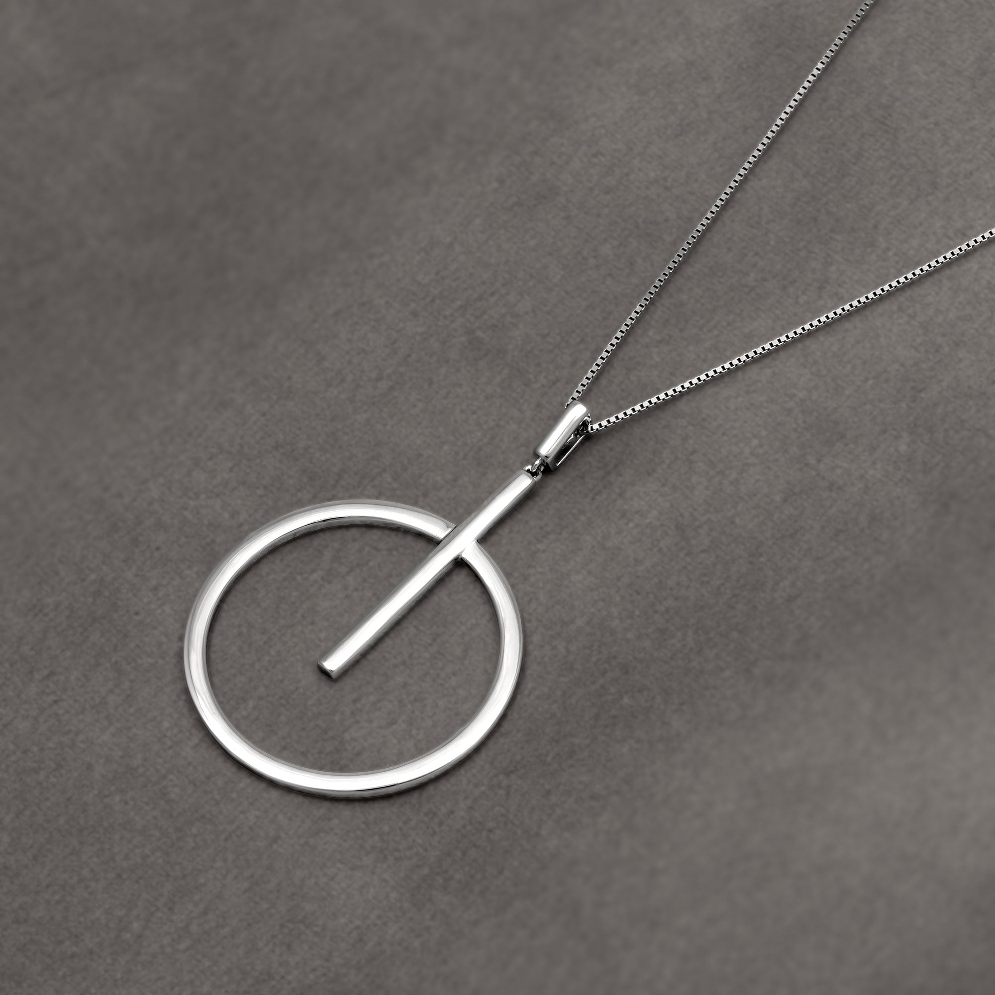 Silver circular pendant on a gray background