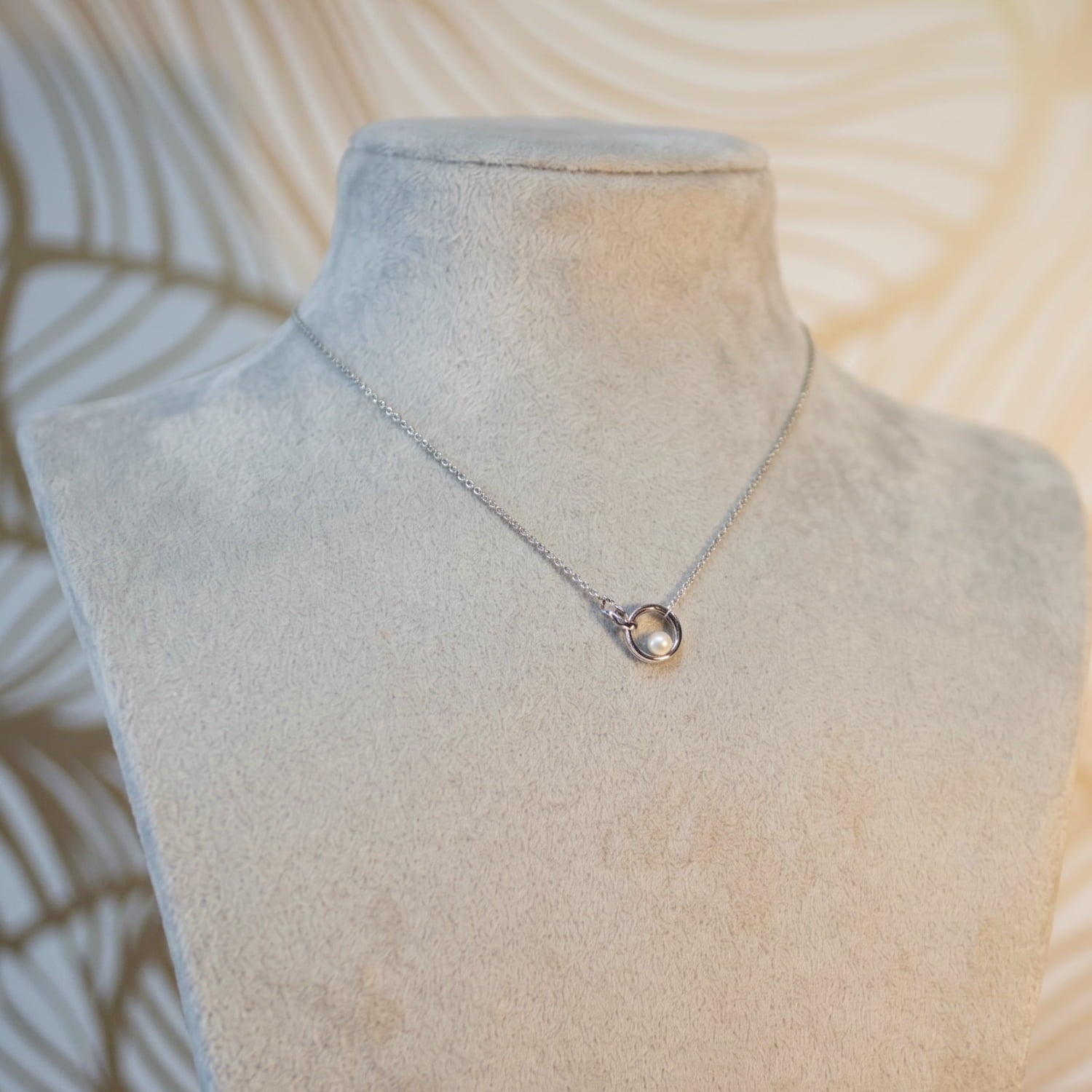A sterling silver necklace with interlocking circle pendants and a freshwater pearl centerpiece.