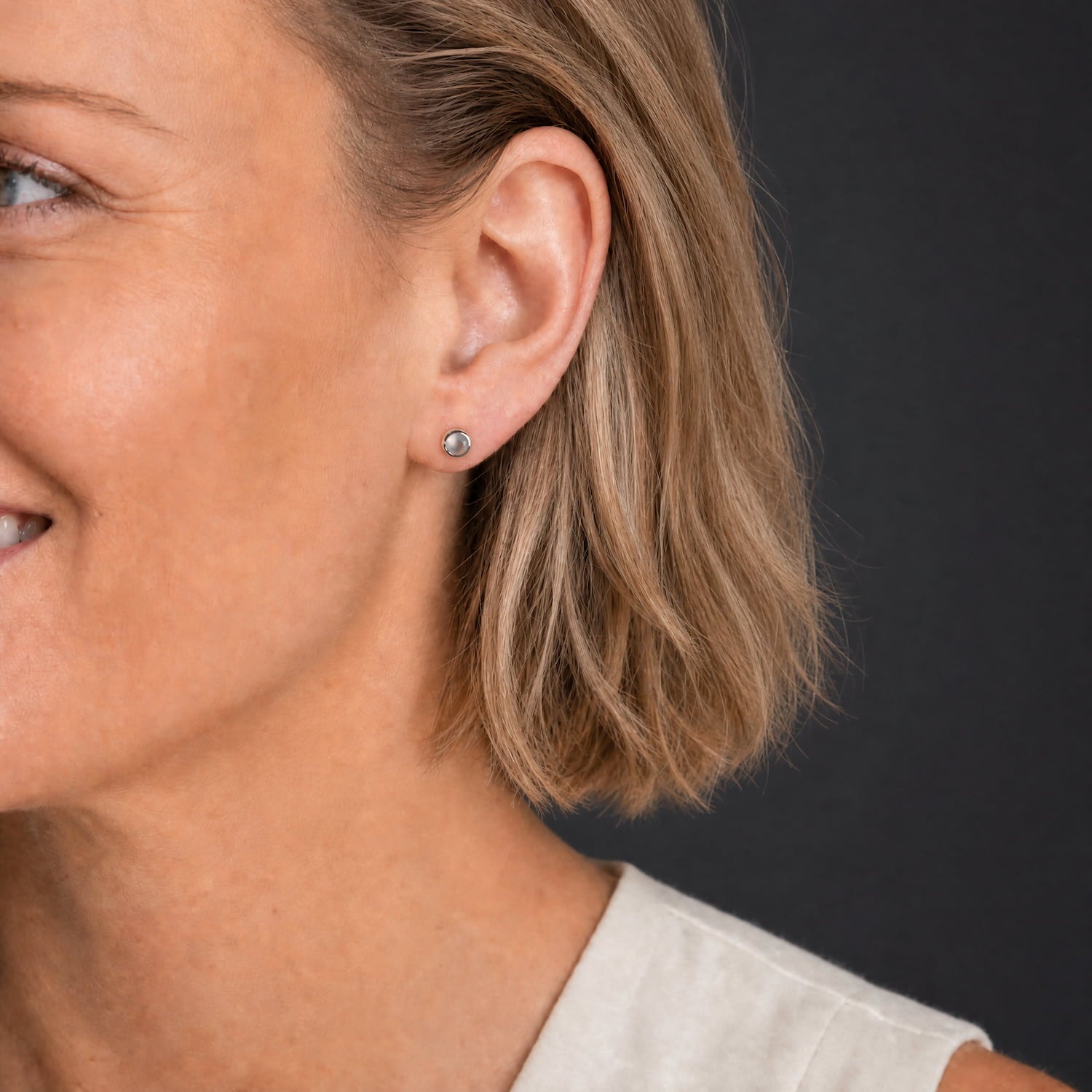 Model wears a pair of sterling silver stud earrings featuring round aqua chalcedony gemstones set in a polished bezel, highlighting refined British craftsmanship.
