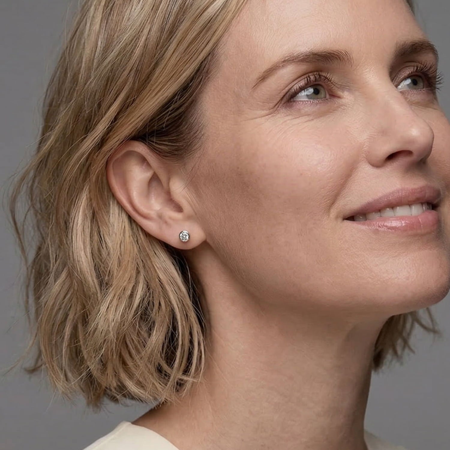 Close-up of a woman wearing elegant sterling silver stud earrings featuring white topaz gemstones, highlighting a refined and sculptural design in a minimalistic style.