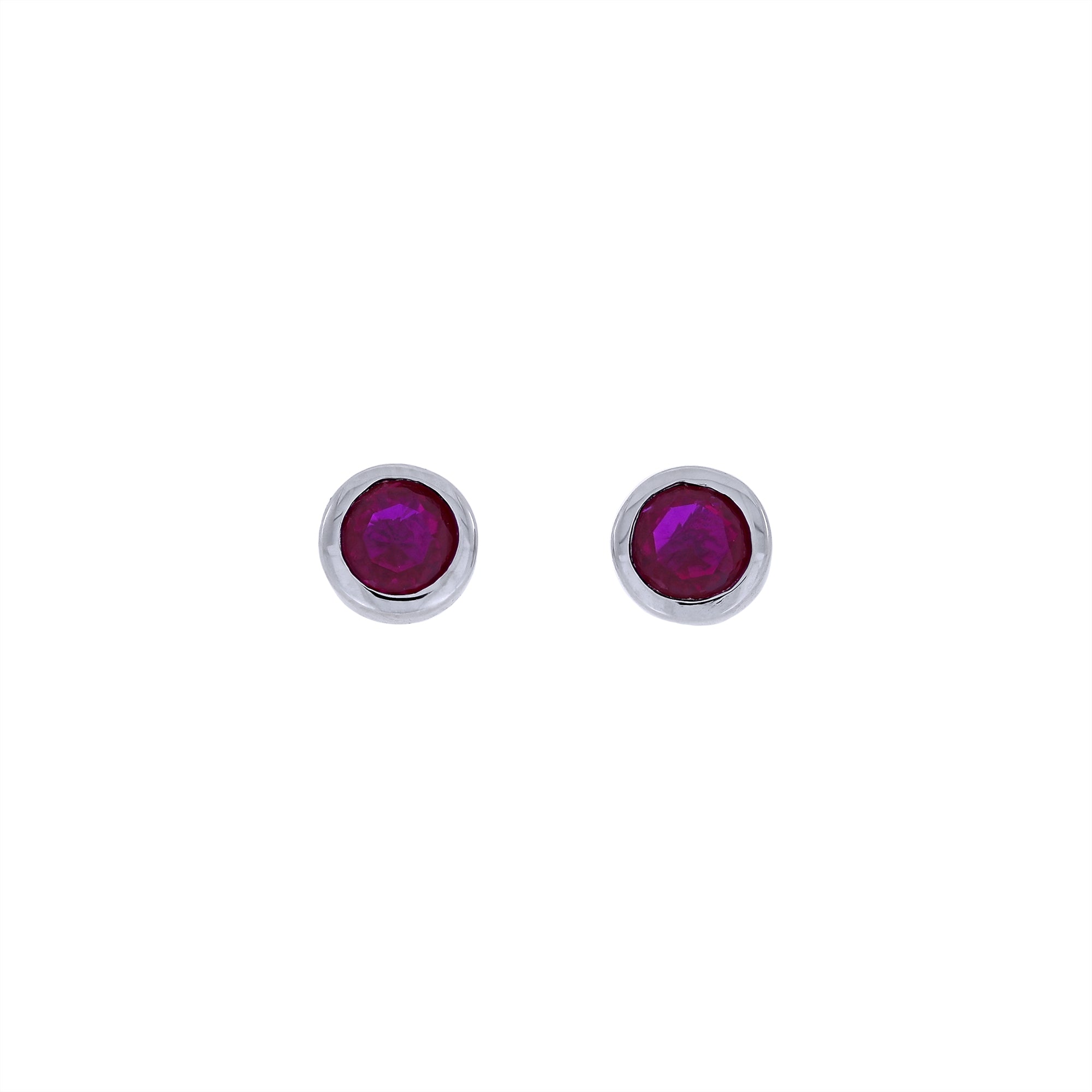 Pair of sterling silver stud earrings featuring deep red ruby gemstones set in smooth bezels, showcasing minimalist yet elegant craftsmanship by a British jeweller.