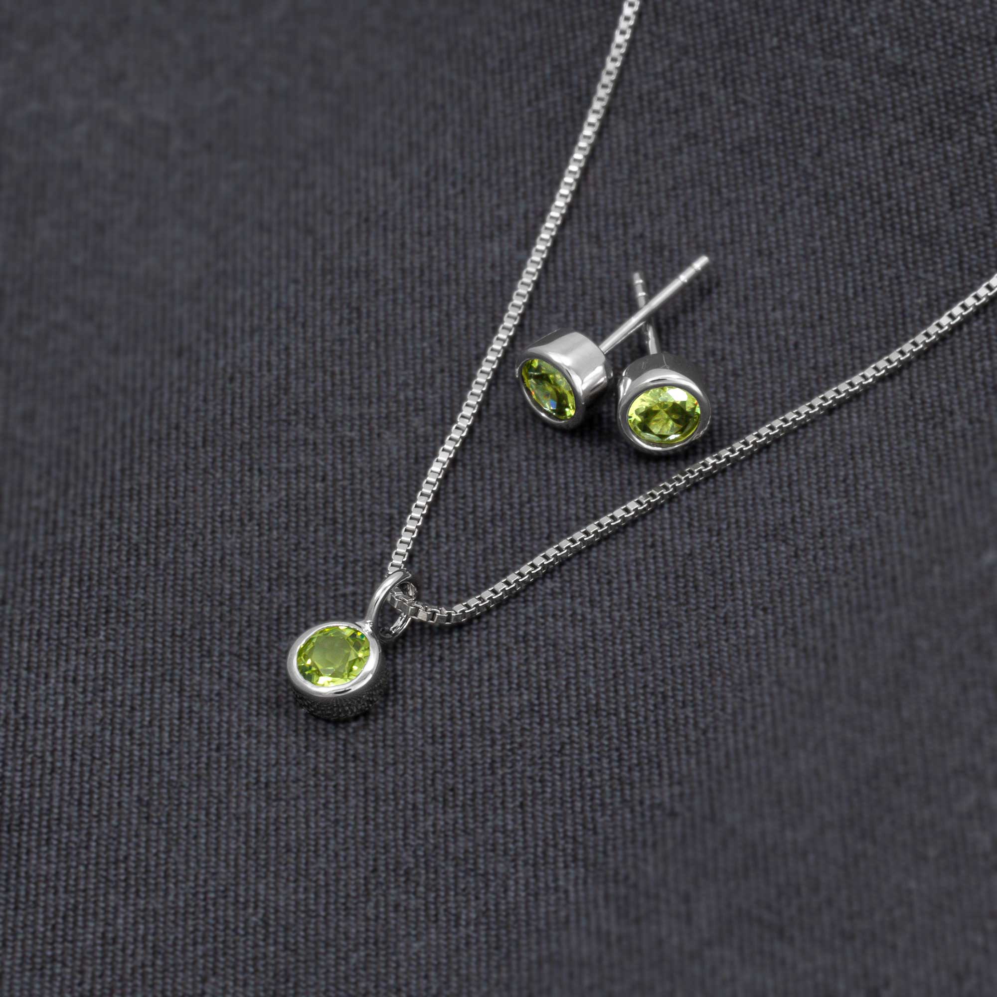Delicate sterling silver earrings featuring vibrant peridot gemstones, paired with a matching pendant on a fine chain, showcasing expert British craftsmanship in sculptural design.
