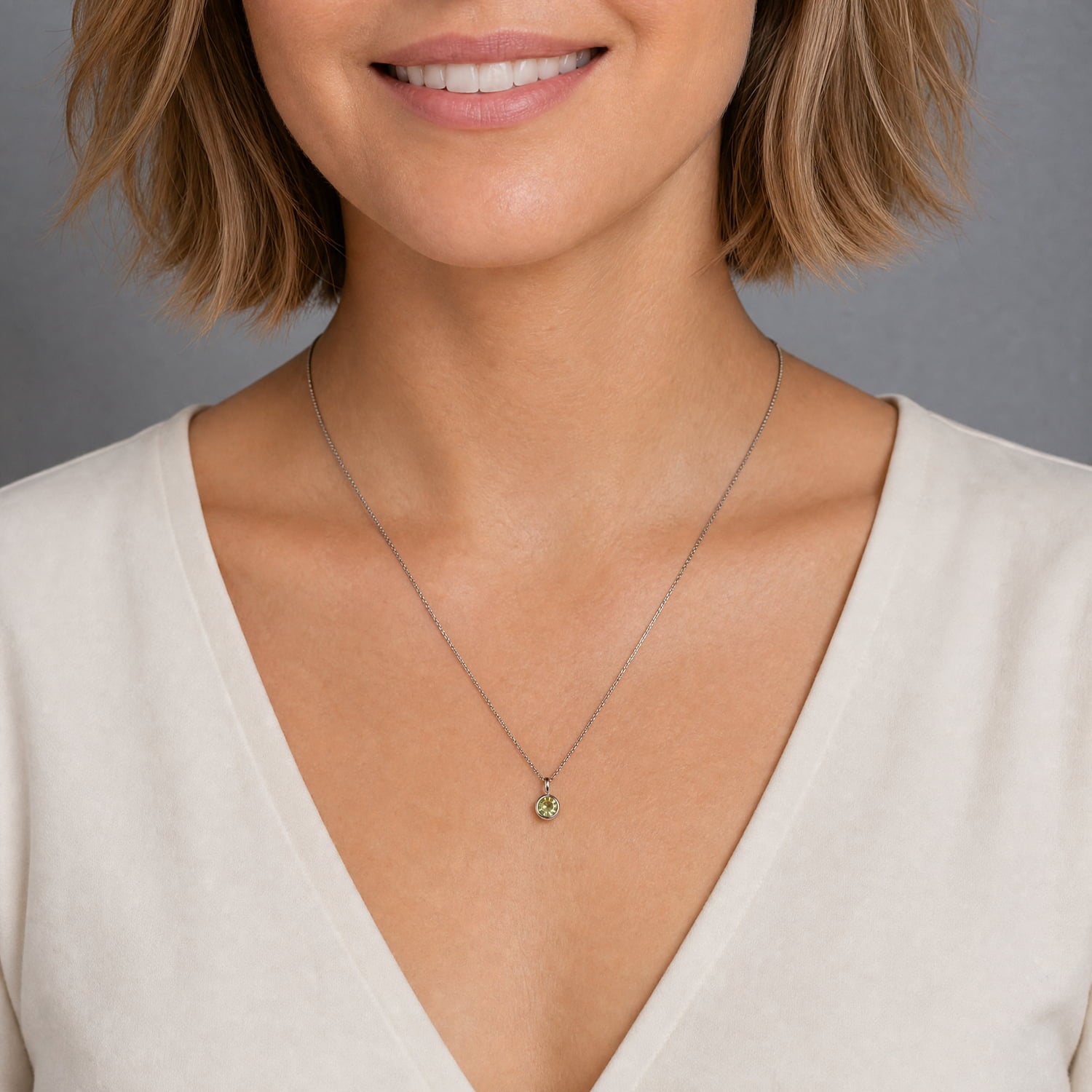 Elegant sterling silver pendant featuring a single round peridot gemstone in a minimalist bezel setting, suspended from a sleek fine chain for a timeless look.