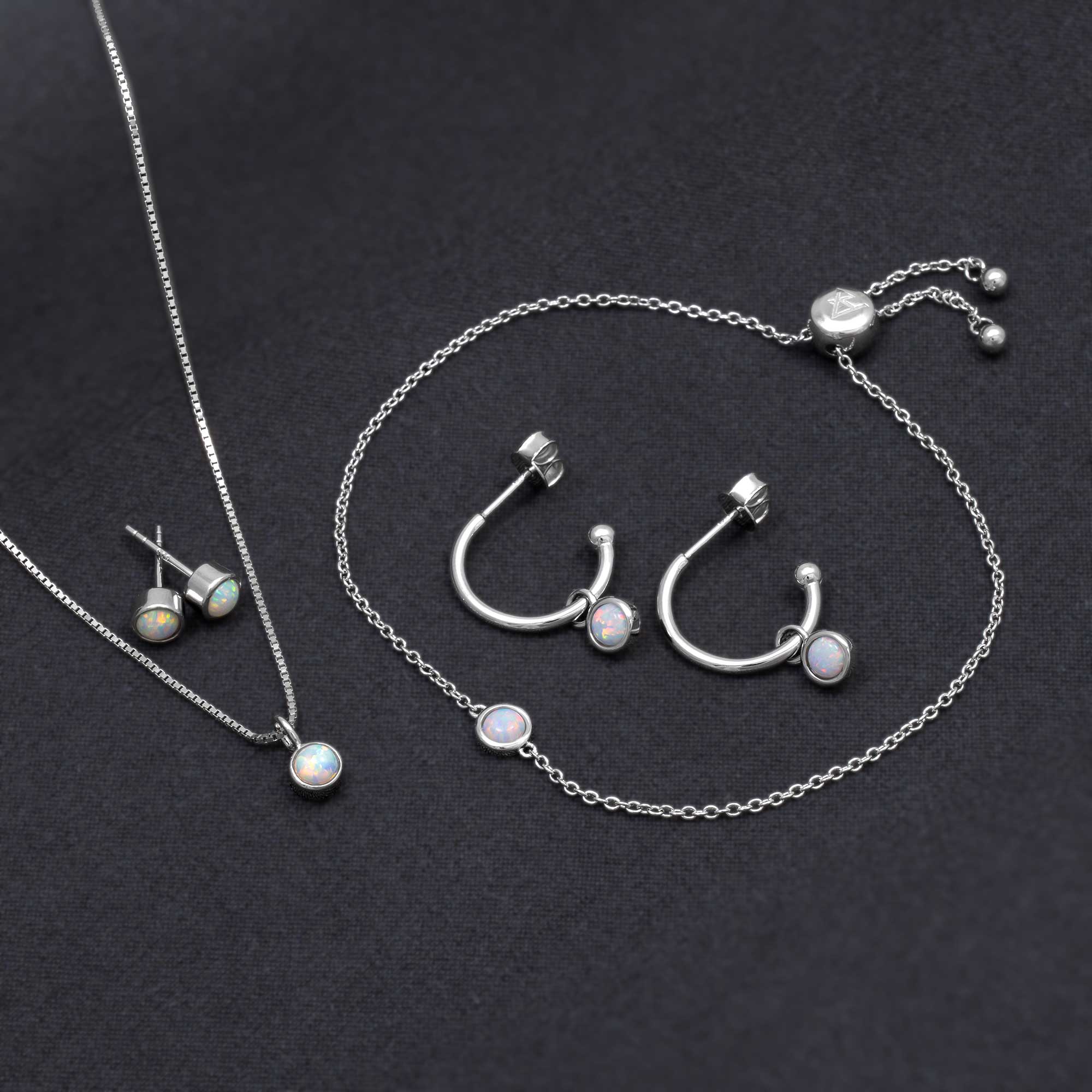 Delicate sterling silver hoop earrings and matching necklace and bracelet set featuring luminous opal stones, reflecting expert British craftsmanship and contemporary design.