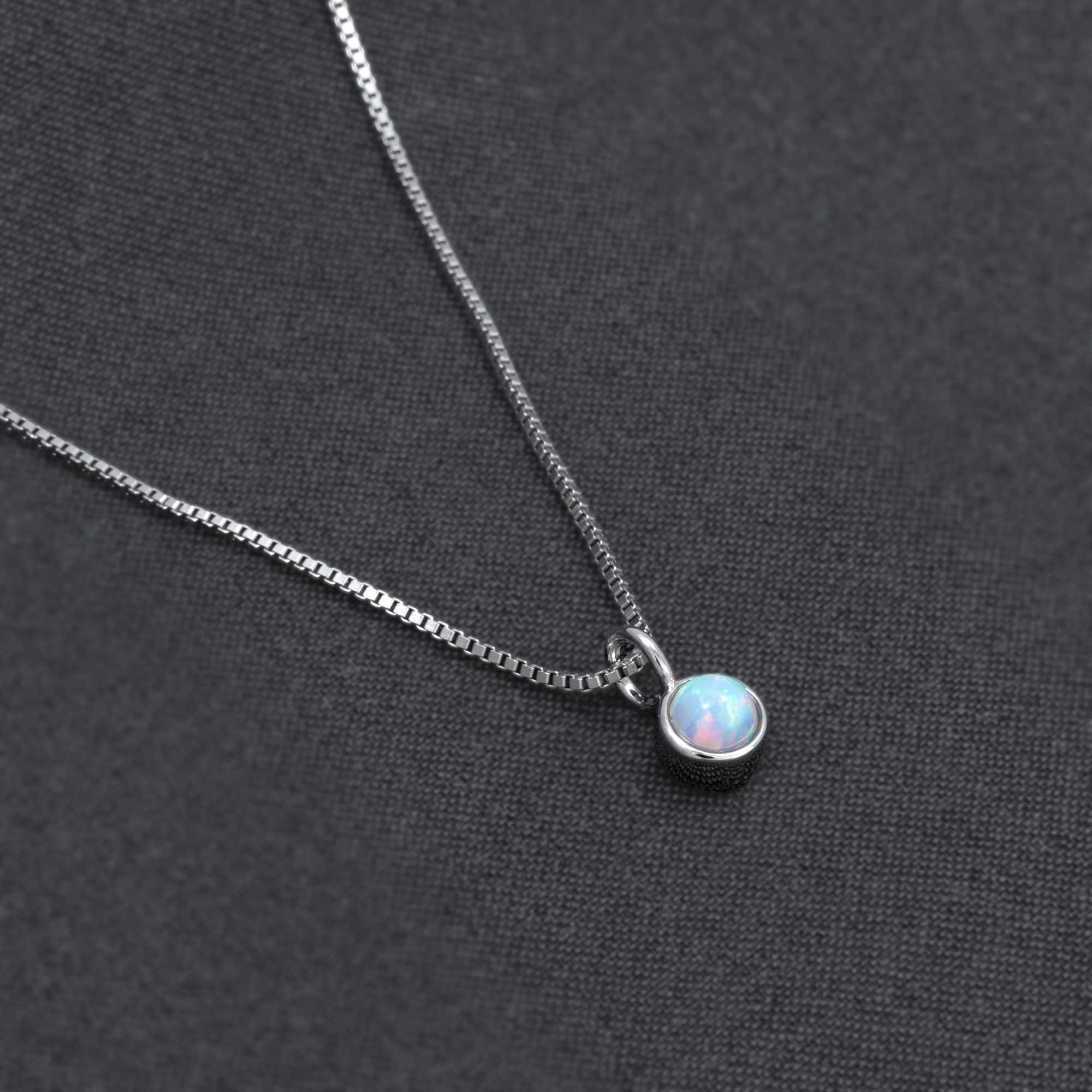 Delicate sterling silver necklace featuring a round opal pendant with subtle iridescence, exemplifying expert British craftsmanship and contemporary design.
